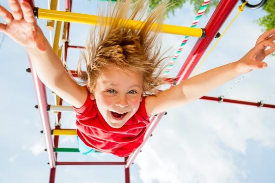 playground concussions - a child dangling upside down on a jungle gym.