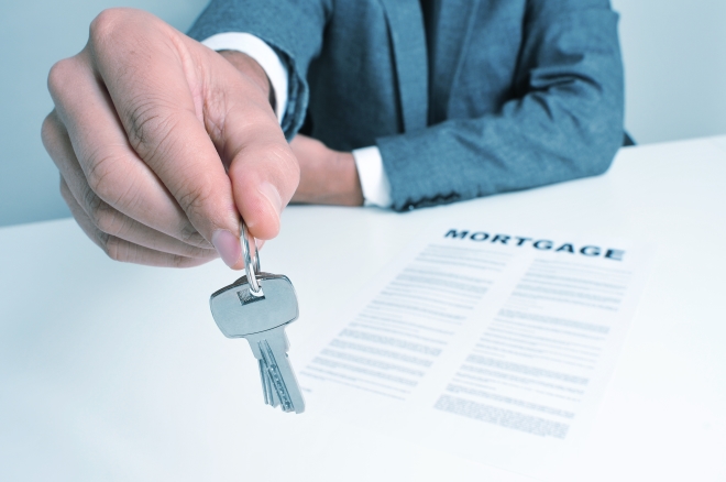 choosing the best mortgage lender - lender passing house keys with mortage document on table