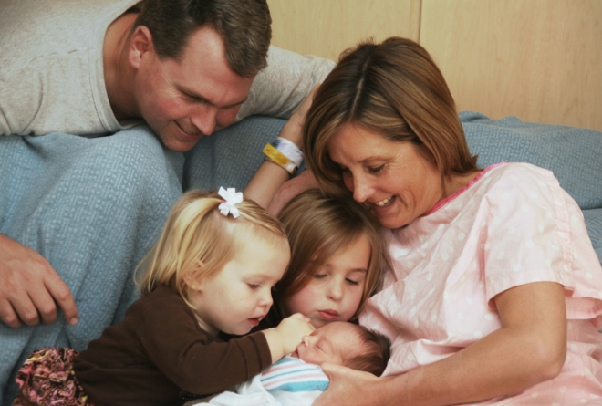 bringing a newborn into a blended family - blended family gathered around mom with new baby