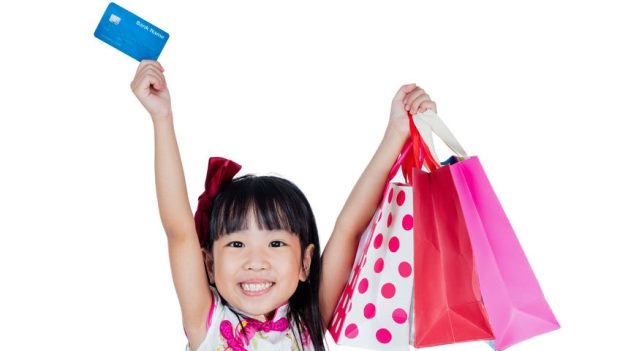 help your kids build their credit score - Asian Chinese little girl wearing cheongsam holding shopping bags with credit card in isolated white background