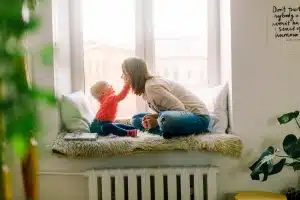 Mom playing with baby in picture window