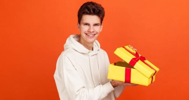 Pleased smiling teenager holding gift box