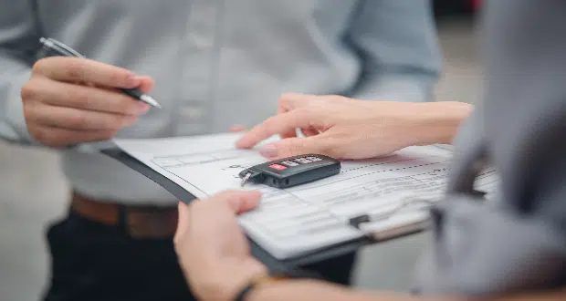 Customer with car dealer agent making deal, sign on agreement document contract in office