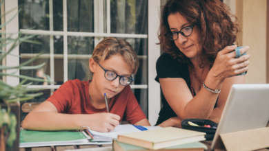 Homeschooling decision for families-Young student doing homework at home with school books newspaper, digital pad helped by his mother.