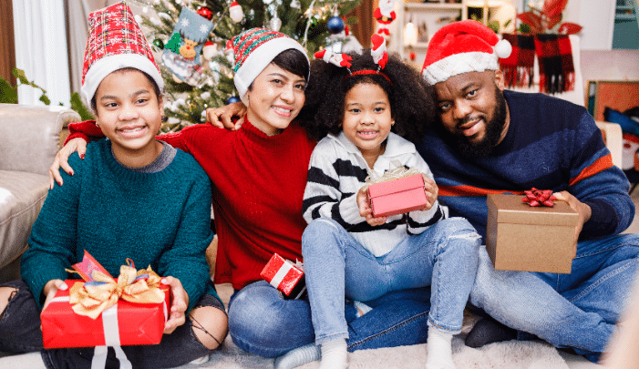 Building New Traditions In A Blended Family: A Stepfather’s Guide To Navigating Christmas-Happy blended family of four bonding sitting on the floor together with Christmas decorations in the living room.