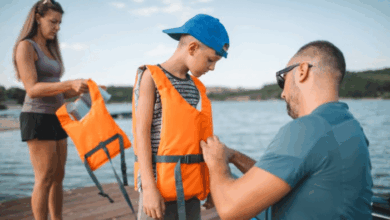 Water safety to prevent drowning-Stepdad helping his stepson put on a life jacket before kayaking