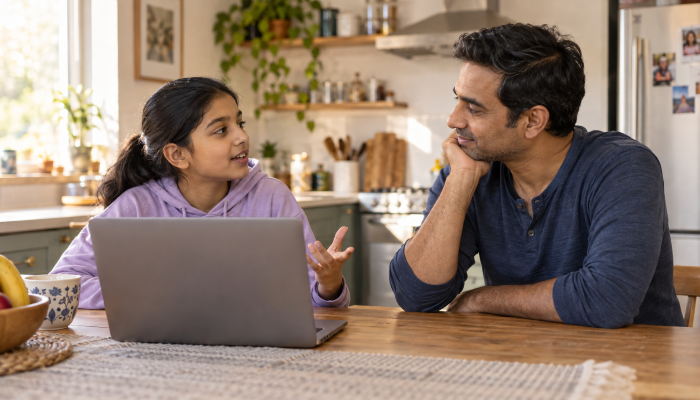 Indian-stepdad-listening-as-his-stepchild-turns-away-from-a-laptop-to-talk